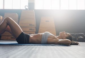 Image depicts a woman bracing her core during core exercises