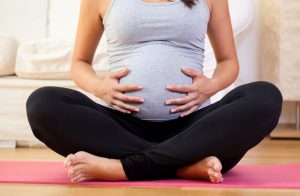Woman sitting on exercise mat during her pregnancy
