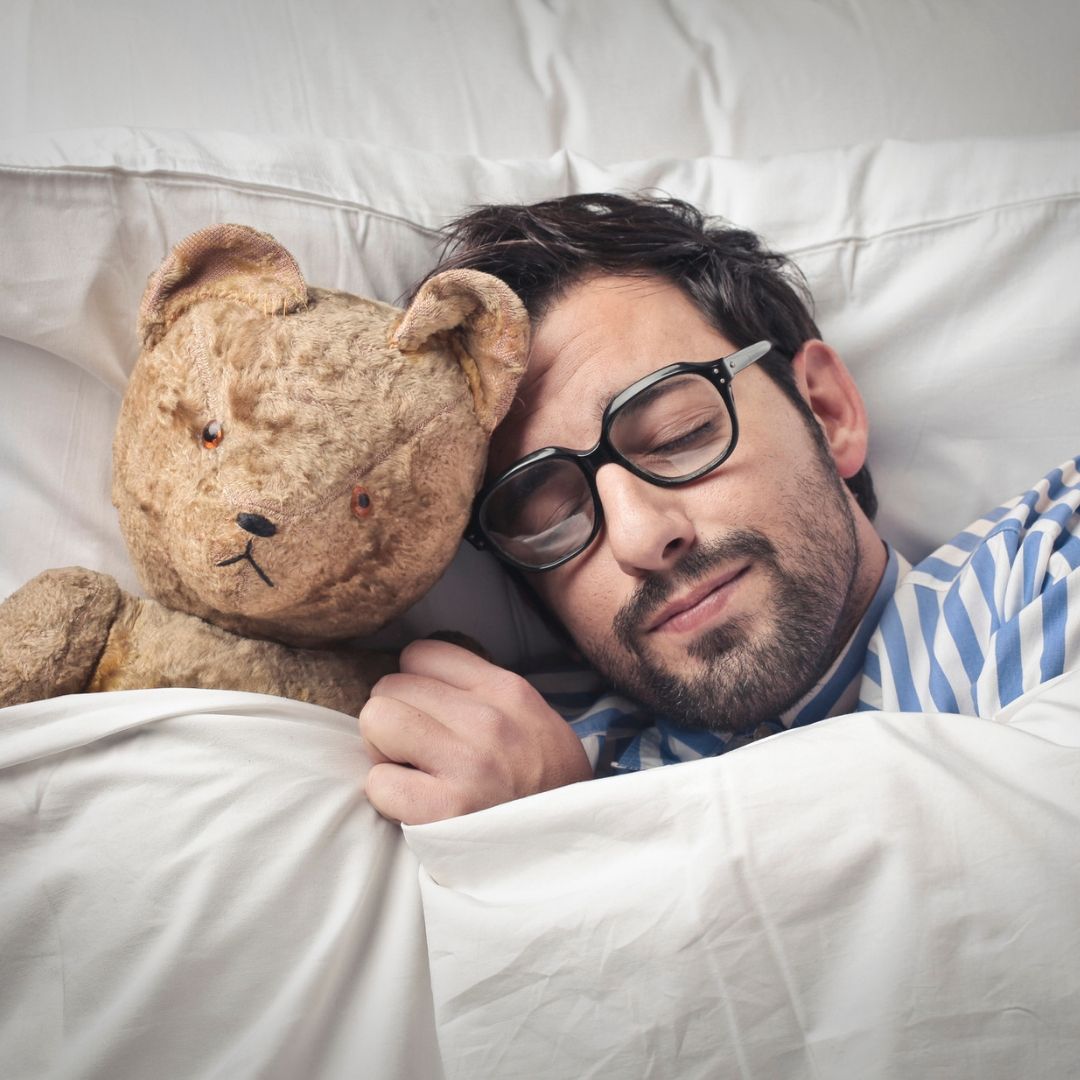 Image of a man getting to sleep with his bear